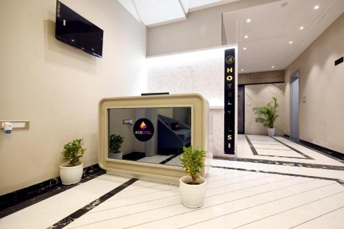 a large tv in a lobby with two potted plants at Aceotel Select Tulsi Vijay Nagar in Indore