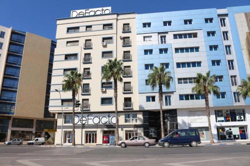 un grande edificio bianco con palme di fronte di Luxury Apartment II Nador Jadid Free Parking & Wifi a Nador