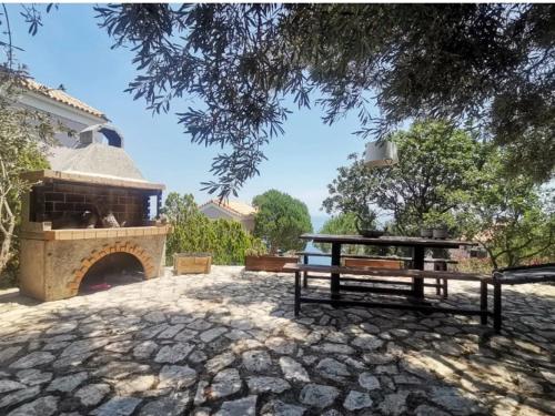 a picnic table and a bench in front of a fireplace at Vigla Villas in Volímai