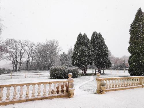 a snow covered park with a fence and trees at Demeure du Haut Canteloup in Honfleur
