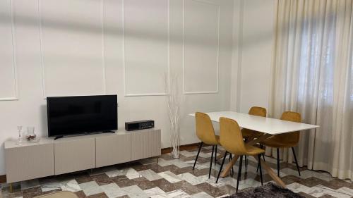 a living room with a table with a television and chairs at Gelsi Apartment - Roma Metro C in Rome