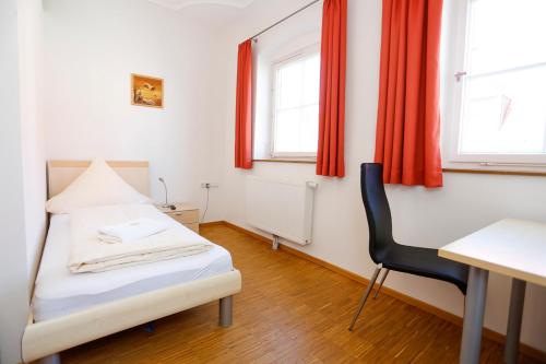 a bedroom with a bed and a desk and a chair at Altstadtpension Friedberg in Friedberg