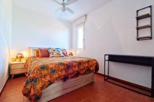 1 dormitorio con 1 cama con colcha de flores y ventana en Apartment Sol Vinaròs con AA Wi-Fi a primera línea y vistas al mar., en Vinarós