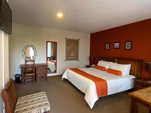 a bedroom with a large bed and a mirror at Capital O La Huerta Golf & Hotel in Cholula