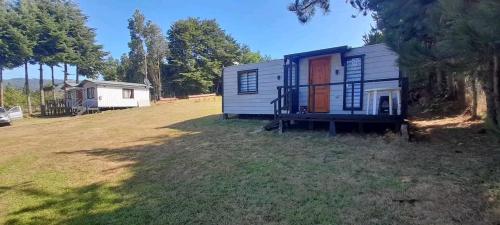 a tiny house sitting in a grass field at CABAÑAS LOMAS DE YECO in Valdivia