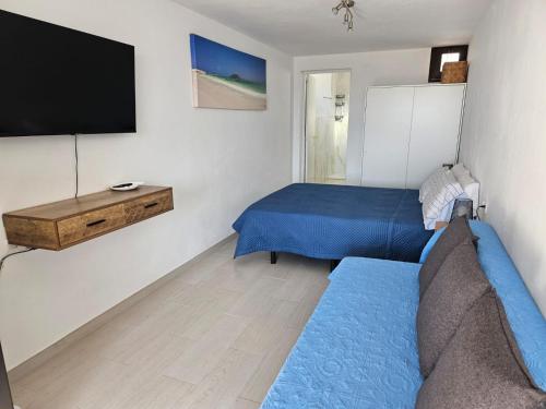 a room with two beds and a flat screen tv at Apartamentos Cotillo Family in Cotillo