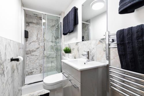 a bathroom with a toilet and a sink and a shower at Luxury Two Bed Apartment with 55in TVs and Netflix in Headingley