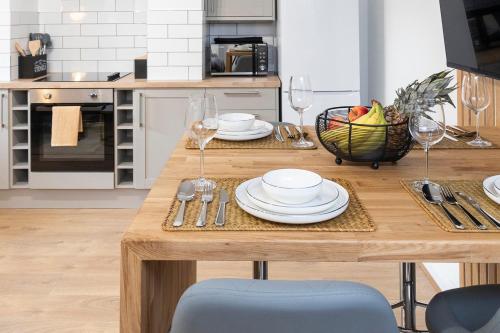 a kitchen with a wooden table with plates and wine glasses at Popular Two Bed Apt in Leeds City in Headingley
