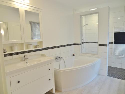 ein weißes Badezimmer mit einer Badewanne und einem Waschbecken in der Unterkunft Wacken Ferienhaus in Wacken