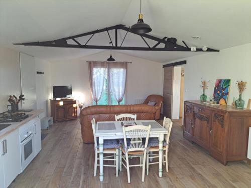 a living room with a table and chairs and a couch at Gîte Les Cerisiers Sud-Gironde dans le Sauternais meublé de tourisme 3 étoiles in Preignac