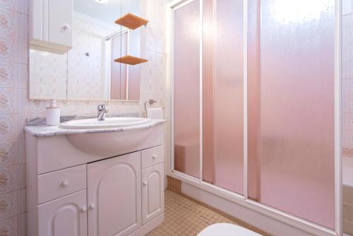 a white bathroom with a sink and a shower at Casa Jardín del Olivar con Piscina privada in Alcaucín