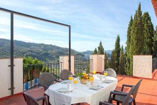 a table on a balcony with a view of the mountains at Casa Jardín del Olivar con Piscina privada in Alcaucín
