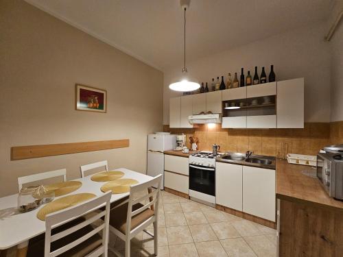 una cocina con armarios blancos y una mesa con sillas. en Apartments & rooms MIKLEUS en Mošćenička Draga
