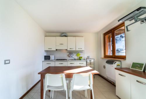 - une cuisine avec une table en bois et des placards blancs dans l'établissement Casa Smile con vista mozzafiato, à Lizzola Alta