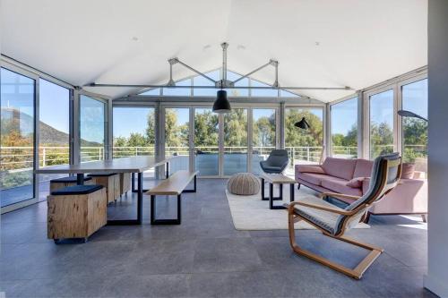 un salon avec une table, des chaises et des fenêtres dans l'établissement L'Amphithéâtre des Volcans - Vue Puy de Dôme, à Saint-Genès-Champanelle
