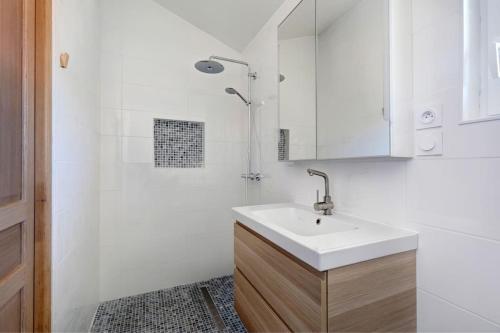 Un baño blanco con lavabo y ducha en L'Amphithéâtre des Volcans - Vue Puy de Dôme, en Saint-Genès-Champanelle