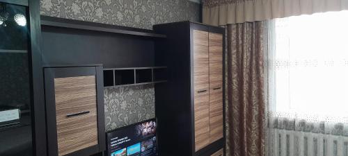Semey في سيمي: غرفة بها دواليب خشبية ونافذة وتلفزيون