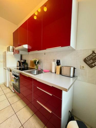 a kitchen with red cabinets and a sink at Attraktive Wohnung im grünen Hinterhof in Schwerin