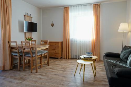 sala de estar con mesa, sillas y sofá en HoFer am Zeitberg Ferienwohnung Ammertal, en Bad Kohlgrub