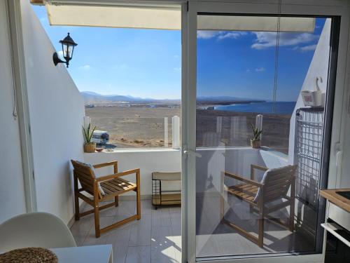 een balkon met stoelen en uitzicht op de oceaan bij Apartamentos Cotillo Family in Cotillo
