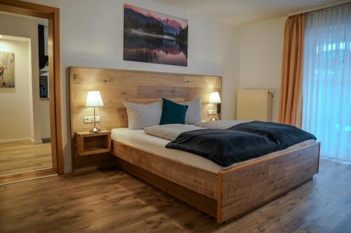 een slaapkamer met een groot houten bed met 2 lampen bij HoFer am Zeitberg Ferienwohnung Echelsbach in Bad Kohlgrub