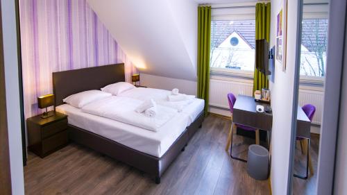 Schlafzimmer mit einem Bett, einem Schreibtisch und einem Fenster in der Unterkunft Hirsch Hotel Hanau in Hanau am Main