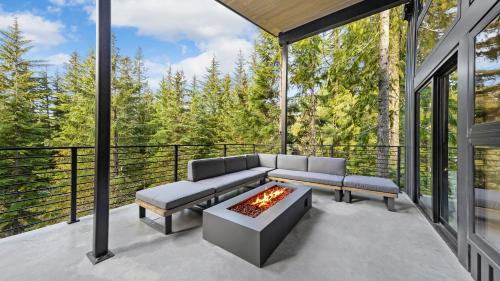 a screened in porch with a couch and a fire pit at RAVN HAÜS - Oregon's Premier Alpine Retreat in Government Camp