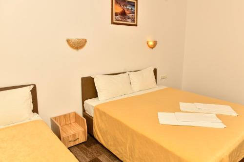 a small room with two beds with yellow sheets at Blyan Family Hotel in Chiflik