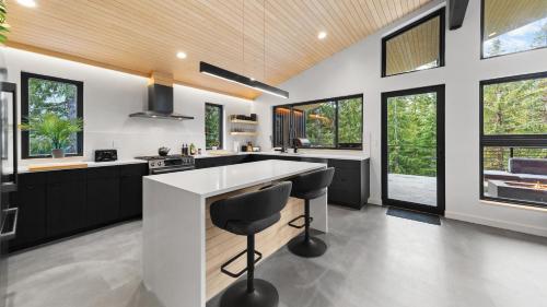 a kitchen with black and white counters and windows at RAVN HAÜS - Oregon's Premier Alpine Retreat in Government Camp