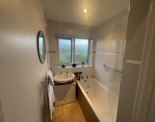 a bathroom with a sink and a tub and a shower at Contractors welcome 3 bed house with parking by Eagle Owl Stays in Crawley