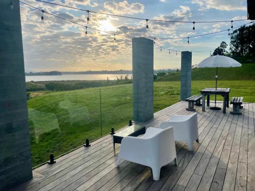 una terraza con 2 sillas, una mesa y una sombrilla en Guesthouse @ Te Puna, en Tauranga