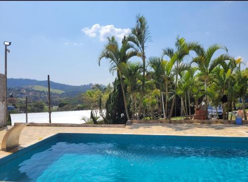a swimming pool with a view of the water and palm trees at Chacara in Atibaia