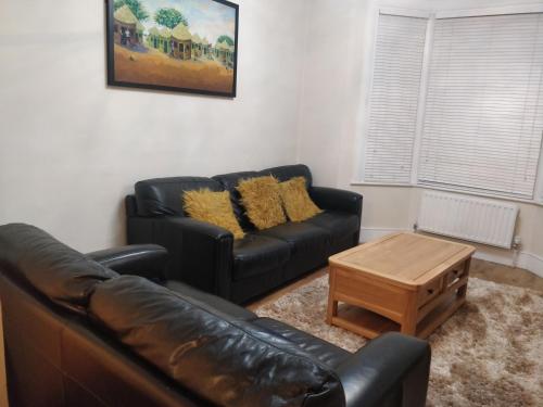 a living room with a leather couch and a coffee table at Whites Place in Slades Green