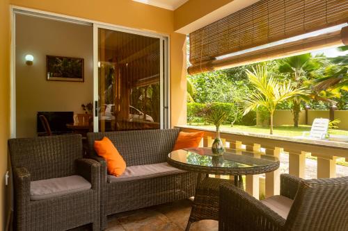 a porch with chairs and a table and a window at Zeph self catering in Baie Lazare Mahé