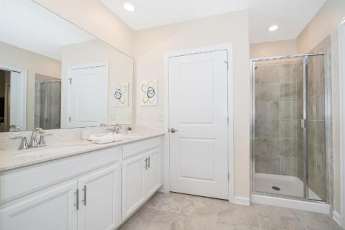 uma casa de banho branca com um chuveiro e um lavatório. em 817JE CHAMPIONS GATE,CONDO + GAME ROOM em Kissimmee