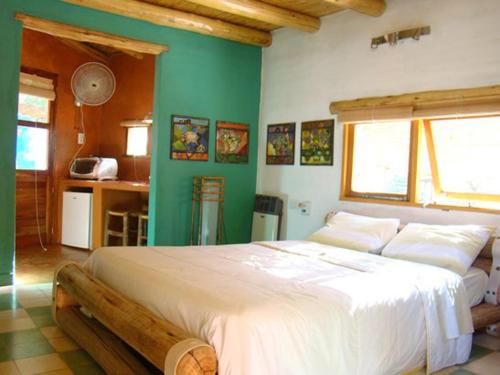 Un dormitorio con una gran cama blanca con paredes verdes. en Posada La Valentina, en Villa Las Rosas