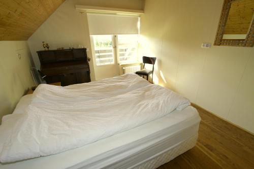 een wit bed in een kamer met een raam bij Artun Guesthouse in Artun
