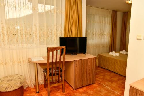 a room with a desk with a television and a bed at Blyan Family Hotel in Chiflik