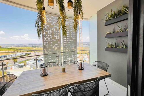 a table and chairs in a room with a large window at Newton’s Place - Luxury styled 2 BD Apartment in Midrand