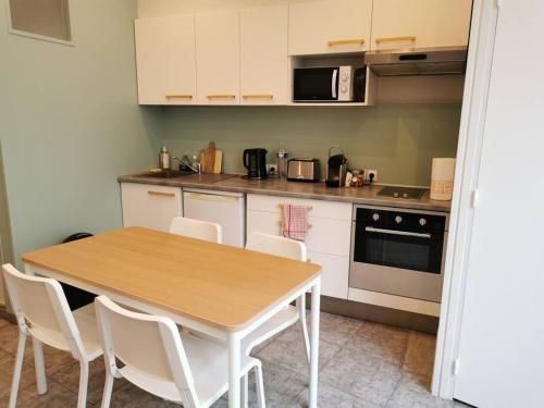une cuisine avec une table en bois et des armoires blanches dans l'établissement Logement 4 personnes tout équipé en centre-ville, à Rouen