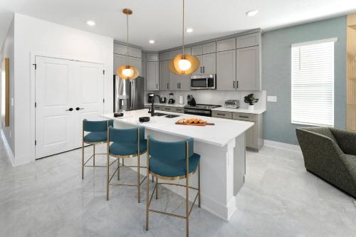 a kitchen with a white counter and blue bar stools at Villatel Orlando Resort in Orlando