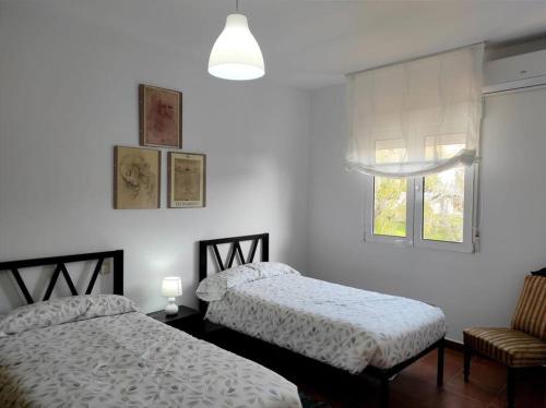 a bedroom with two beds and a window and a chair at Casa con Jardín entre Toledo y Puy du Fou in Toledo