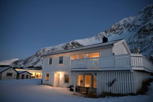 una casa blanca en la nieve frente a una montaña en Leilighet med strandbeliggenhet, en Ramberg
