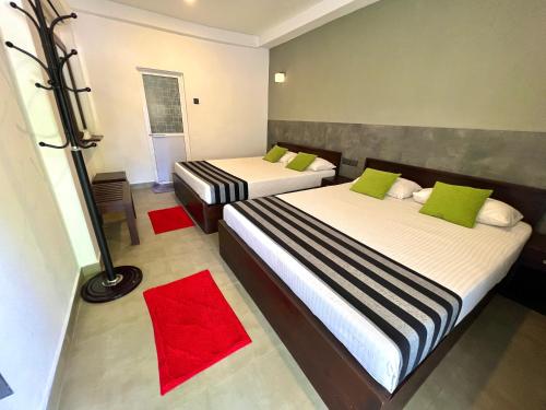 two beds in a room with two red rugs at DELMOND Lake - Anuradhapura in Anuradhapura