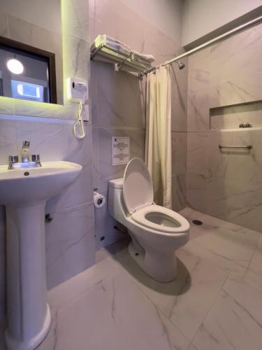 a white bathroom with a toilet and a sink at Hotel Principal in Mexico City