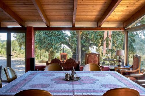 een eetkamer met een tafel, stoelen en ramen bij Finca Heredad La Boquilla in Enguera