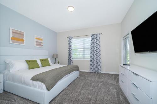 1 dormitorio blanco con 1 cama y TV de pantalla plana en 1137GV CHAMPIONS GATE,CONDO + GAME ROOM, en Kissimmee