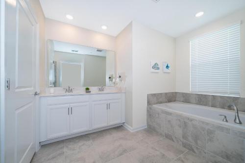 Baño blanco con bañera y lavamanos en 1137GV CHAMPIONS GATE,CONDO + GAME ROOM, en Kissimmee