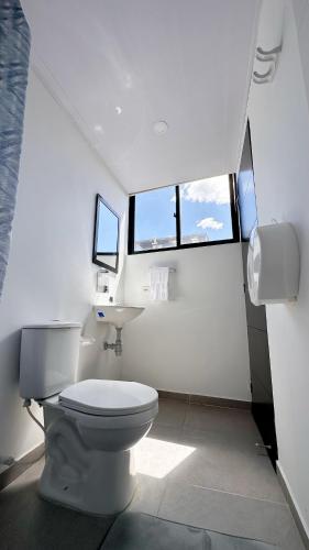 a white bathroom with a toilet and two windows at Loft 60 Movistar arena 403 in Bogotá