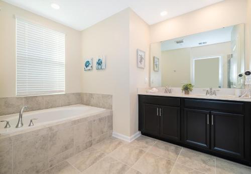 een badkamer met een bad, 2 wastafels en een spiegel bij 1147CR CHAMPIONS GATE,CONDO + GAME ROOM in Kissimmee